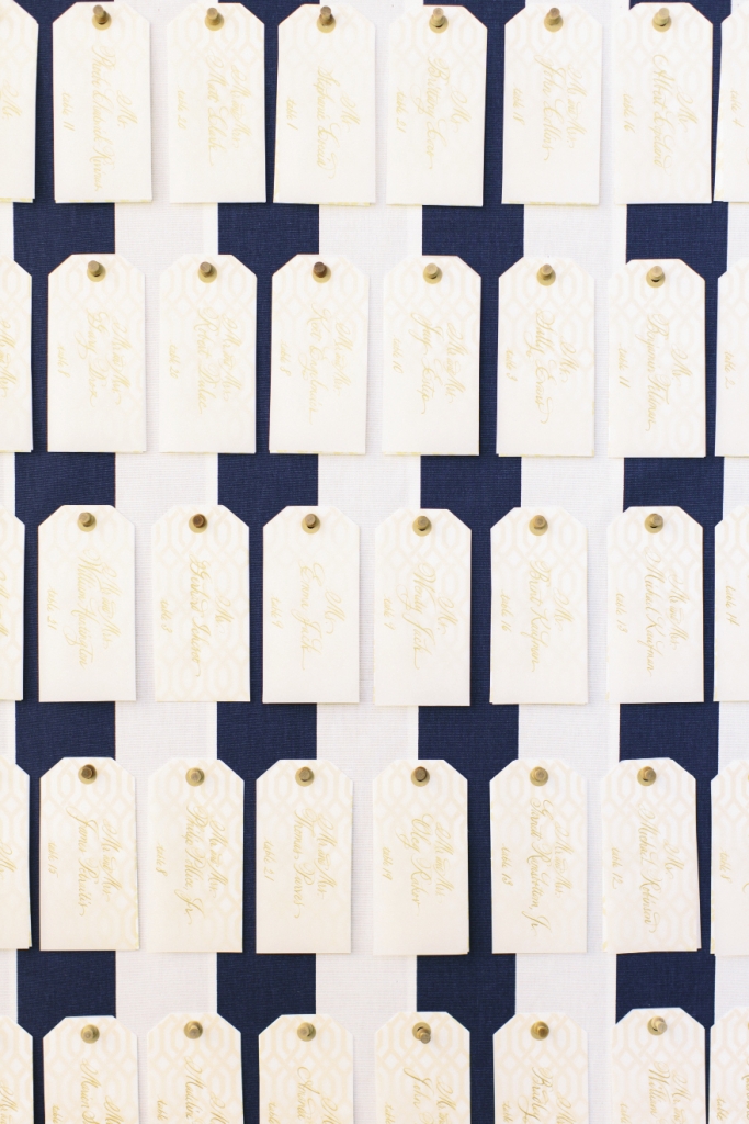Posted with wooden thumbtacks, paper luggage tags sporting the same pattern as the wedding’s reply card were  calligraphed to direct guests to their tables.
