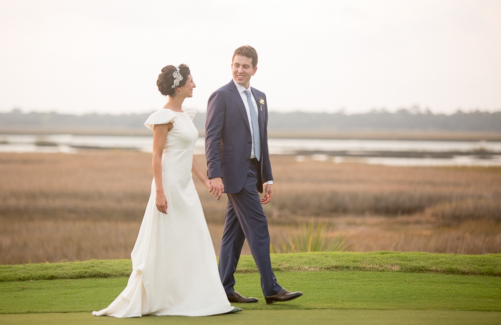 Bride&#039;s gown by Delphine Manivet. Menswear by SuitSupply. Photograph by Captured by Kate at River Course at Kiawah Island Club.