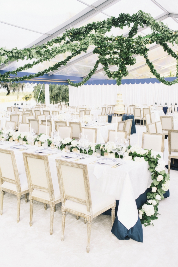 To transform the open-air tent into a black-tie reception hall, Tara and her team laid down cream-colored carpet, hung garlands of fresh greens braided with twinkling lights, and draped tables in custom floor-length linens. The head table was marked with a verdant 29-foot floral runner.
