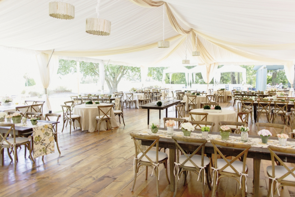 LUXE LIFE: The dining hall tent, with its honey-toned wooden floors, mercury-glass drum shades, and gently gathered fabric draping, was an oasis of elegance in the open field.