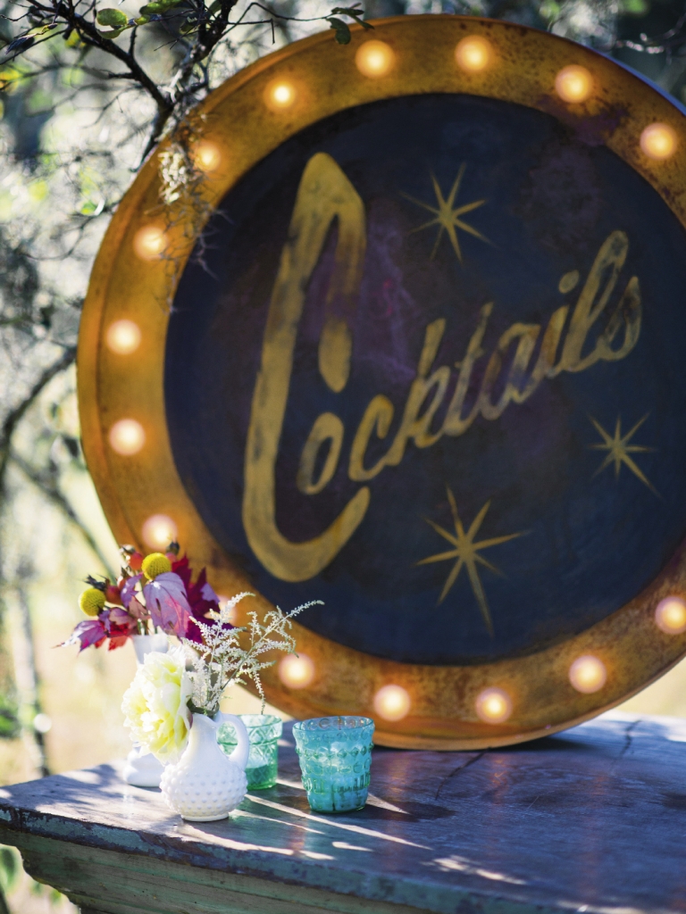 DRINKS ON US: A 1920s “Cocktails” sign from Ooh! Events cast a glamorous glow over the zinc-topped bar.