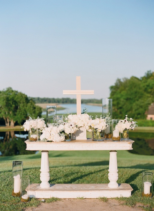 WHITE WEDDING: Dusty miller, lamb’s ears, lilac, peonies, ranunculus, spray roses, tetra anemones, and Queen Anne’s Lace dressed an altar from Snyder Events. Colors were kept simple so as not to detract from the natural beauty.