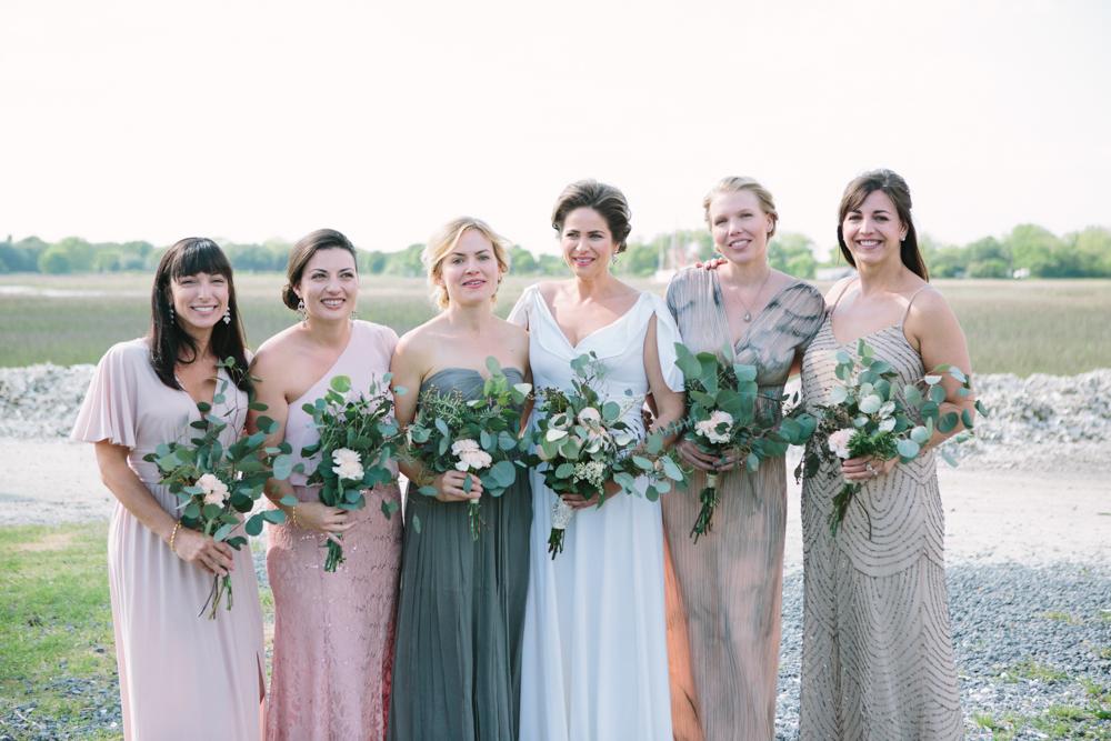 Bridesmaids’ dresses from personal wardrobes. Bride’s gown from her mother, altered by Jean’s Bridal. Bouquets by bride and friends. Hair by Patrick Navarro. Makeup by Madison Hughes Makeup.  Image by Susan Dean Photography at Bowens Island Restaurant.