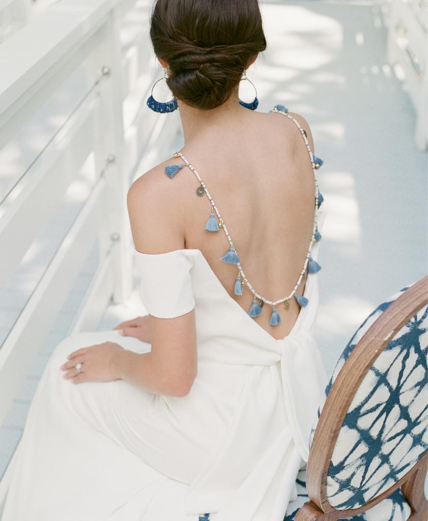 Lela Rose’s “The Capri” off-shoulder gown from Maddison Row South. Lapis beaded earrings and Balinese tassel necklace, both from Celadon Home. C. Gonshor’s diamond and platinum ring from Diamonds Direct. Chair from Ooh! Events