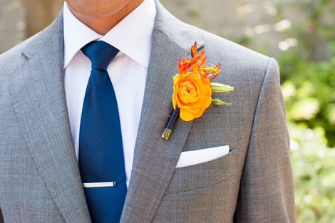 FINISHING TOUCH: The groom&#039;s papaya-hued boutonnière popped against his gray suit, and the navy blue tie echoed the hue of the bridesmaid frocks.