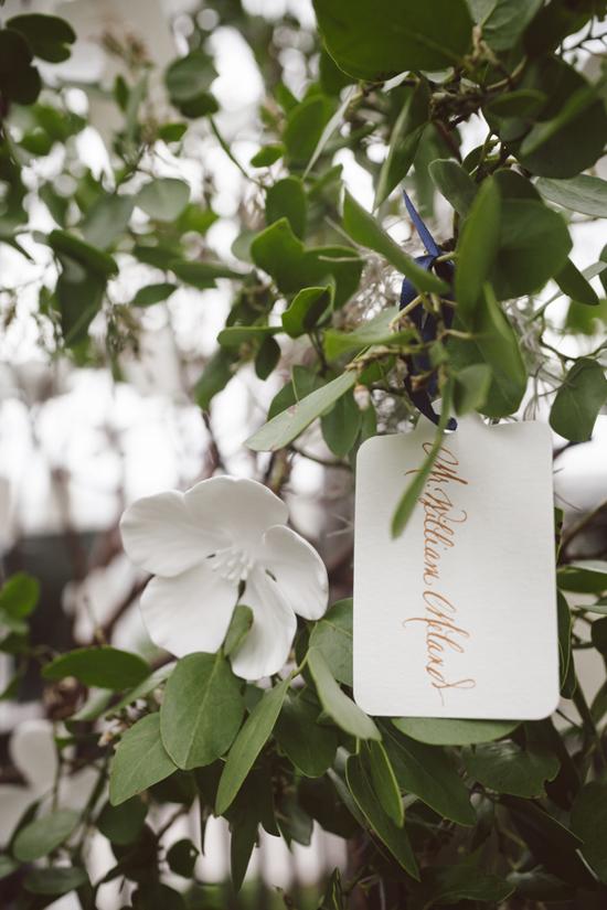 GOLDEN TICKET: Escort cards were printed with gold ink to tie in the gold foil found throughout the rest of the event’s paper goods. The porcelain flowers that were wired to the trees were given out as favors.