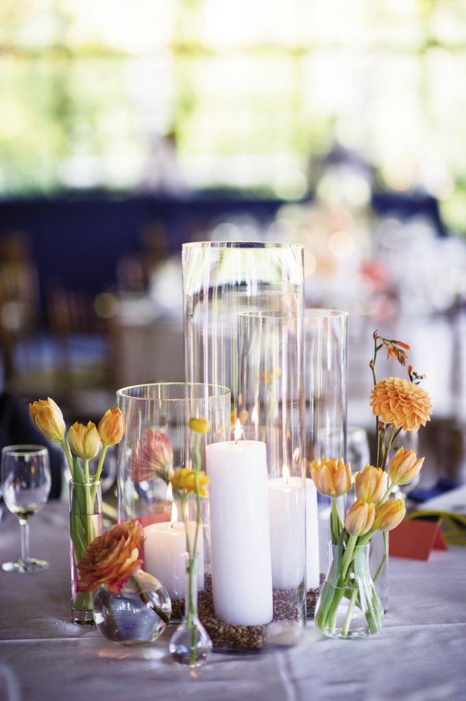 CENTER OF ATTENTION: Blooms with varying textures and shapes in shades ranging from orange to peach accented simple clear glass hurricane vases to form sophisticated centerpieces.