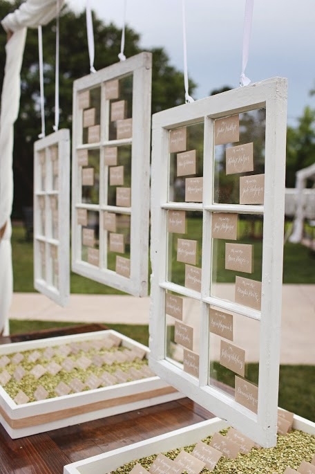 CLEAR AS DAY: Engaging Events adhered escort cards to vintage window panes for an open, airy look. Below, they placed cards atop green split peas. “We use these boxes often to display escort envelopes using different mediums depending on the weddings’ colors and design,” says Jessi Martin of Engaging Events.  In this case, it looked rustic, chic, and organic”
