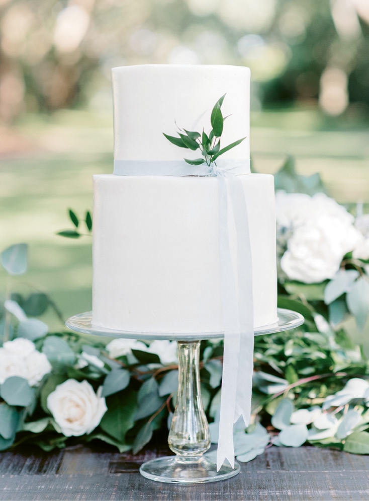 A white buttercream cake punctuated with greens and a simple silk ribbon tied into the thoughtful design. (Photo by Aaron &amp; Jillian Photography)