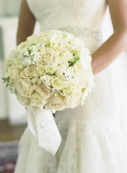 SPHERE OF INFLUENCE: Ashley carried a bouquet by Soirée of white roses, peonies, spring tulips, lisianthus, and stephanotis. A monogrammed silk ribbon garnished the bundle