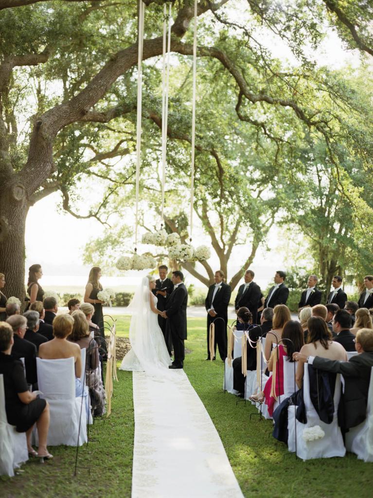 HANGING GARDEN: Chandeliers adorned with roses, peonies, lisianthus, and tulips were hung with champagne-hued ribbon to frame the open-air “altar.”