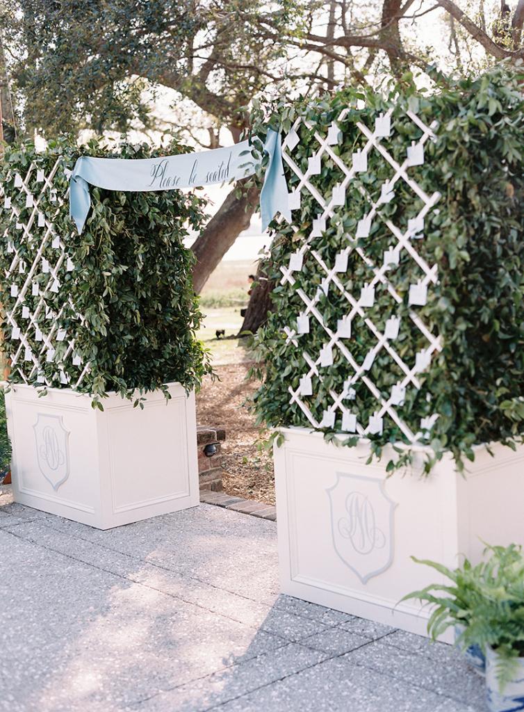 A silk banner in French blue with white lettering read, “Please be seated” and beckoned the 100 guests from the cocktail party to the reception. Escort cards were tucked into the boxwood entrance that was made especially for the evening.