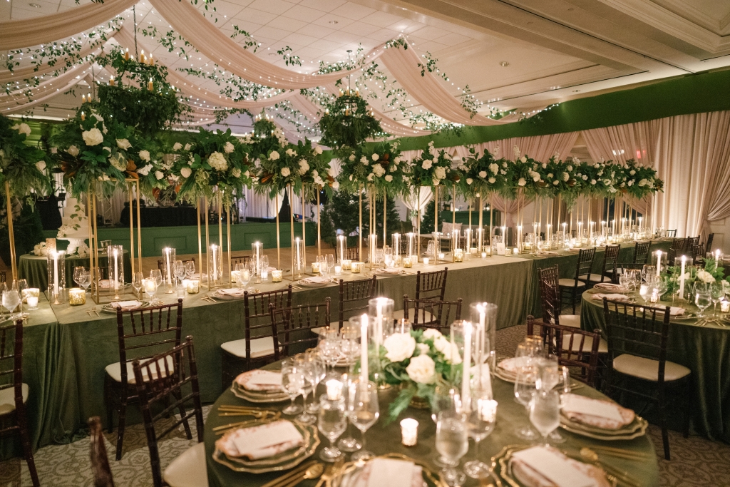 Hundreds of taper and votive candles reflected off glassware and gold-rimmed china and cutlery to set an elegant tone for the reception, which was decked in evergreens, garden roses, ranunculus, hellebores, gardenia, and freesia.