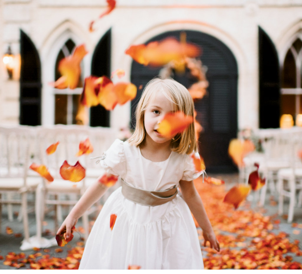 To harken fall foliage, Loluma gave this downtown wedding a fiery runner of ombré orange rose petals that the flower girl couldn’t resist. (Photograph by Sean Money + Elizabeth Fay)