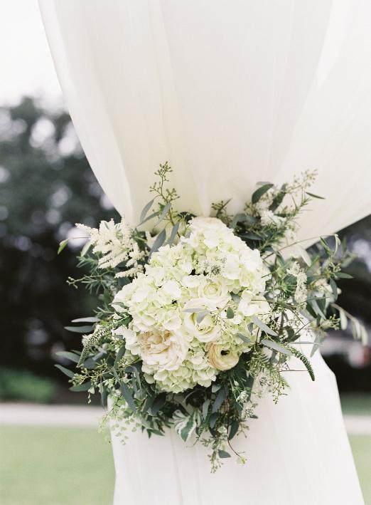 Curtain tie-backs were punctuated with bundles of garden roses, hydrangeas, and seeded  eucalyptus from Sarah York Grimshaw Designs.