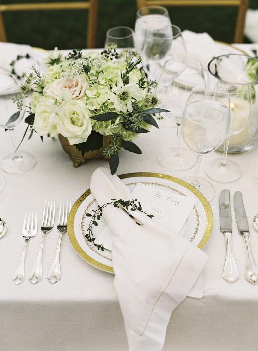 Snyder Event Rentals’ “Imperial Gold” china lent a formal tone to place settings that were finished with the company’s “King James” silver-plated flatware and hemstitched linen napkins accented with fresh garlands of angel vine.