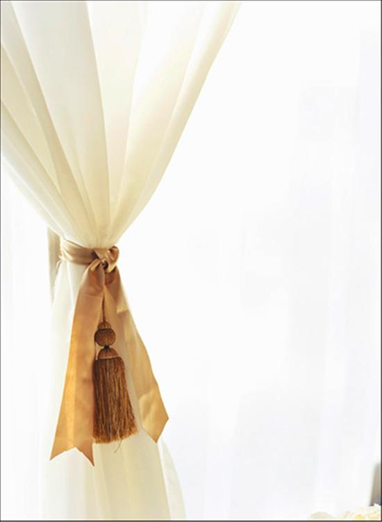 SEEING DOUBLE: Décor from the ceremony was tied into the reception—panels of sheer fabric were held back by silk ribbon accented with tassels.
