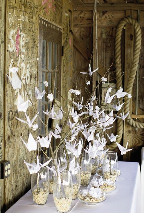 FLOCK TOGETHER: Paper cranes and flowers hung off branches rooted in stone-weighted vases.