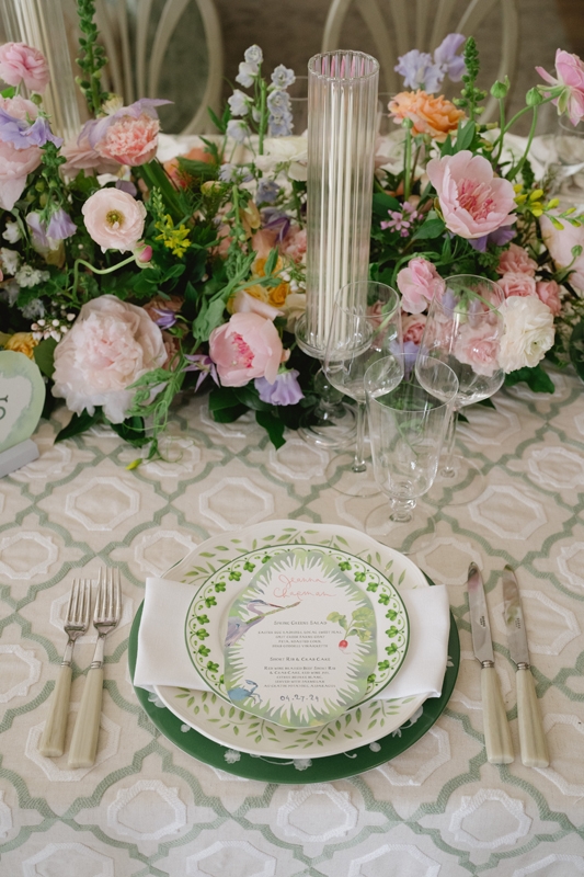 Stationer Happy Menocal Studio adorned the whimsical place cards/menus with a blue crab and heron. At the center of each table, roses, peonies, and other spring florals surrounded candles set in optic glass sleeves.