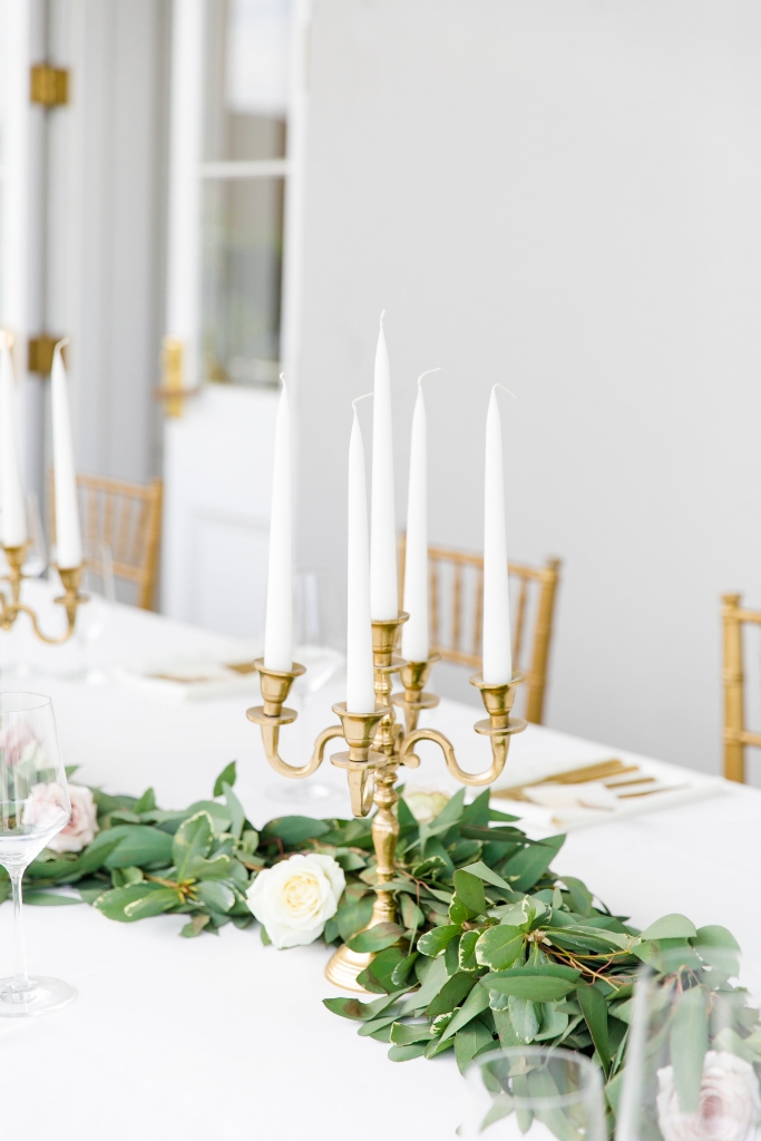 TIP: Pair shiny gold with shimmering crystal and mercury glass. Toasting flutes rimmed with gold, a glass cake stand with a hammered gold base, brass candelabras, and a collection of golden mercury glass-style vases echoed the subtle sparkle without overpowering the setting.  Image by Dana Cubbage Weddings