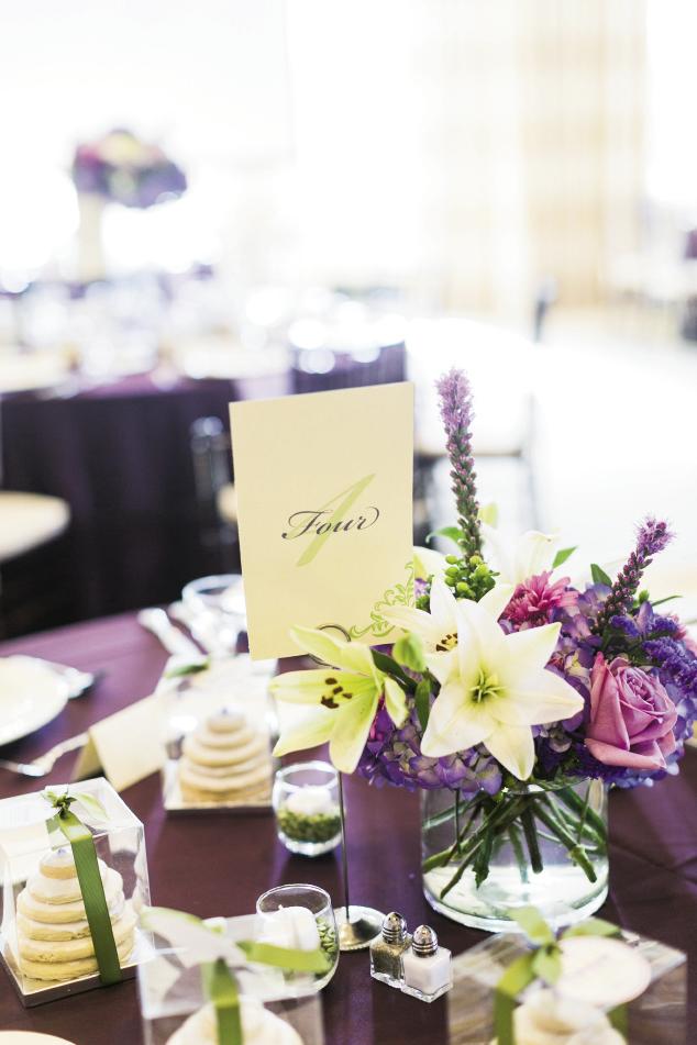 WHAT A TREAT: Tables covered in bold purple linens were topped with purple stock, fuchsia roses, purple blazing star, and white lilies by OK Florist. Erica’s mother, aunt, and cousins made miniature “cake” favors from stacked cookies they iced together.