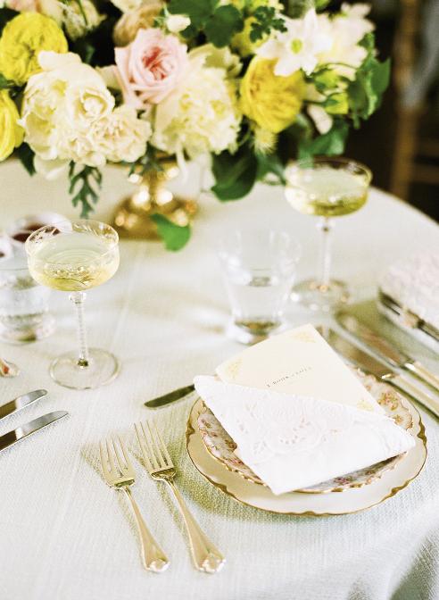 IN THE FOLD: Kristin Newman Designs tucked the couple’s “Book of Love” menu into a folded Battenberg lace napkin and placed it atop hand-selected heirloom china. Etched champagne coupes—a shape  originally designed for English aristocrats—finished the look on the sweetheart table.