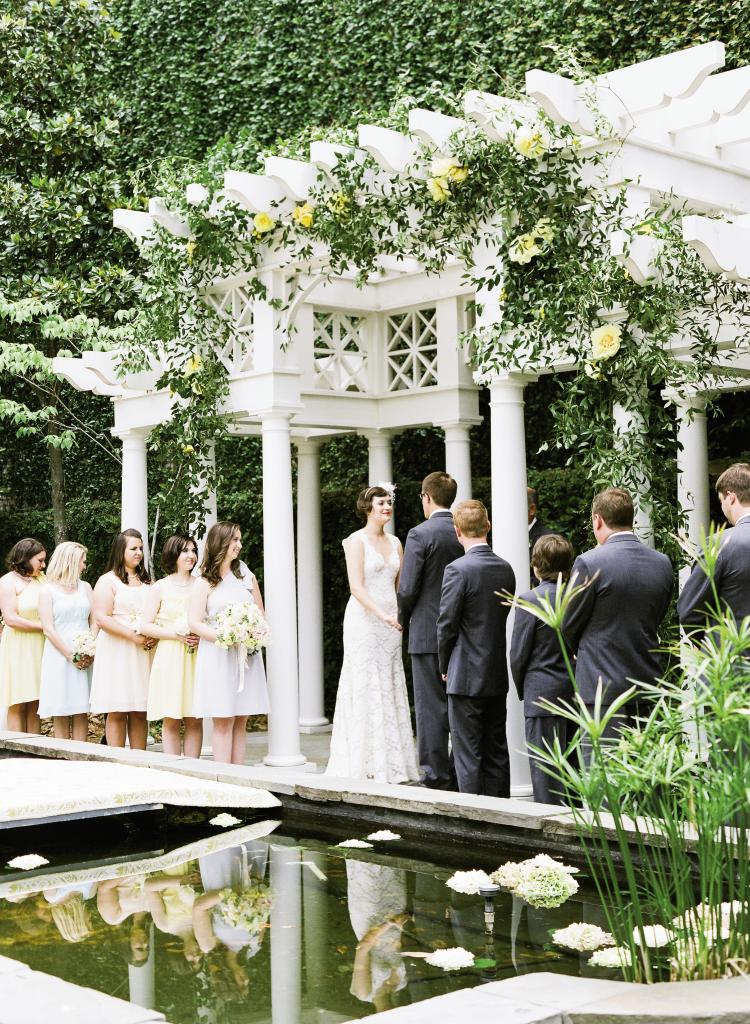 NEW HEIGHTS: Gathering Events turned the  William Aiken House’s arbor  into a garden trellis with a  meandering vine of smilax and  yellow peonies—the bride’s favorite flower. Hydrangea blooms floated in the lily pond, which was spanned with a temporary bridge covered with a damask-style runner.