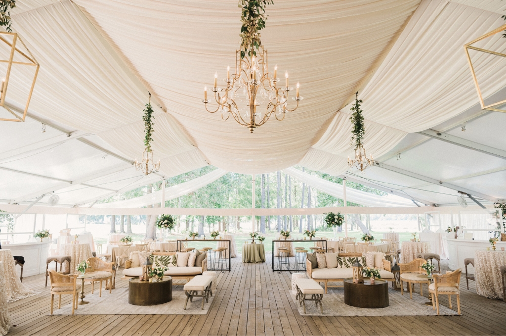 In the reception tent, elegant draping and a mix of hanging lanterns and chandeliers helped achieve the semi-rustic and glam aesthetic. The various textures, neutral hues amid pops of greenery, and a harmonious arrangement of traditional sit-down tables and lounge furniture created a breathtaking and welcoming environment.