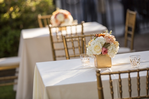 LOW PROFILE: Be mindful of conversation when planning your reception centerpieces. These gold boxes with short stems of roses and hydrangeas in the wedding’s hues add impact while being practically sized.