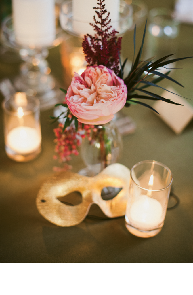 As a subtle nod to Halloween, table  assignments were attached to golden masks, which guests donned for a masqueraded beachfront cocktail hour. (Image by Juliet Elizabeth Photography)