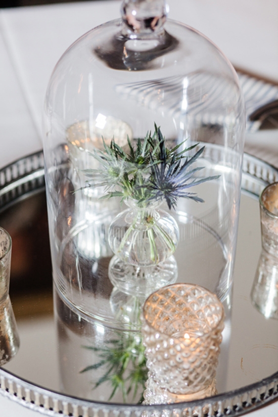 UNDER COVER: Turn a simple flower (like this thistle) and budvase into a curiosity centerpiece when you cover it with a glass cloche. One other trick? Placing it atop a mirrored tray doubles the volume and gives the illusion of centerpiece larger than life.