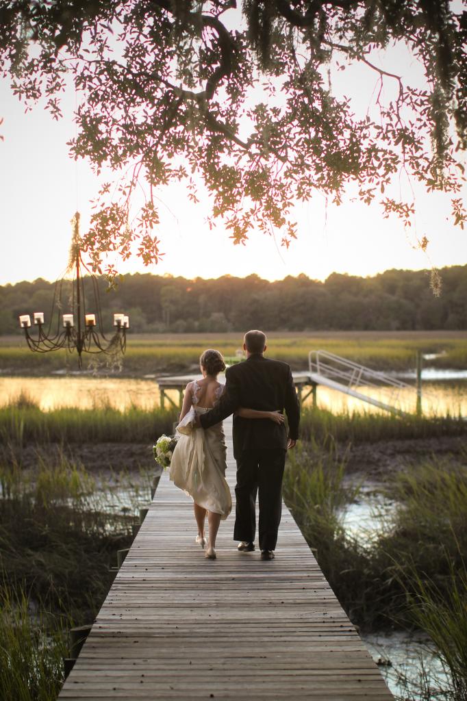LET’S WALK: The newlyweds took a sunset stroll down the dock. Behind them dangled RiverOaks’ trademark item—a rustic chandelier draped in Spanish moss.