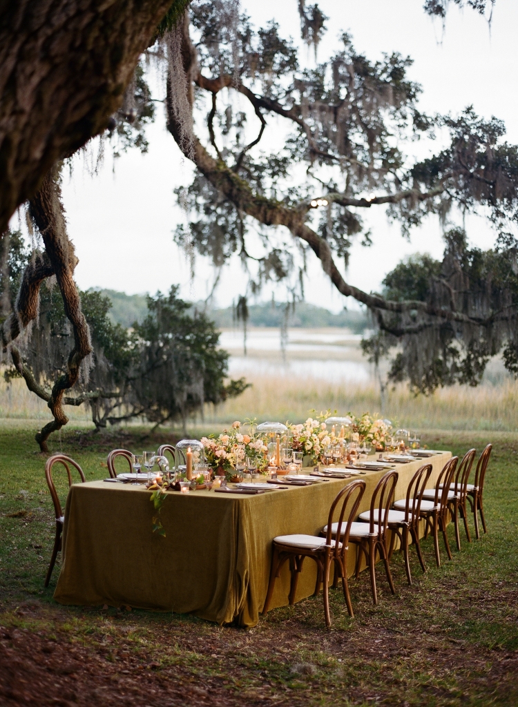 At Kiawah River, this table for 12 was bedecked in green velvet, custom porcelain dinnerware from Parisian designer Marie Daâge, candles, cloches, nuts, seeds, and frilly blooms like gloriosa lilies, ranunculus, sweet peas, and hellebores. The family-centered wedding focused on quality over quantity.