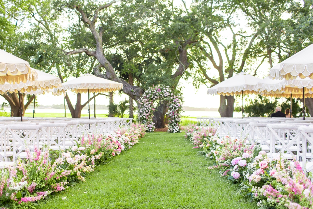 For the riverside nuptials, Blossom Bay dressed the aisle and archway with roses, peonies, snapdragons, dianthus, godetia, and larkspur