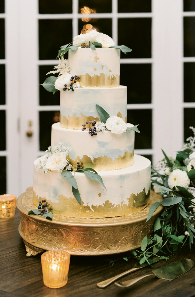 Accented in edible gold leaf, the four-tiered dessert held layers of almond, vanilla, and lemon poppy seed cake iced in buttercream that was painted in a watercolor style.