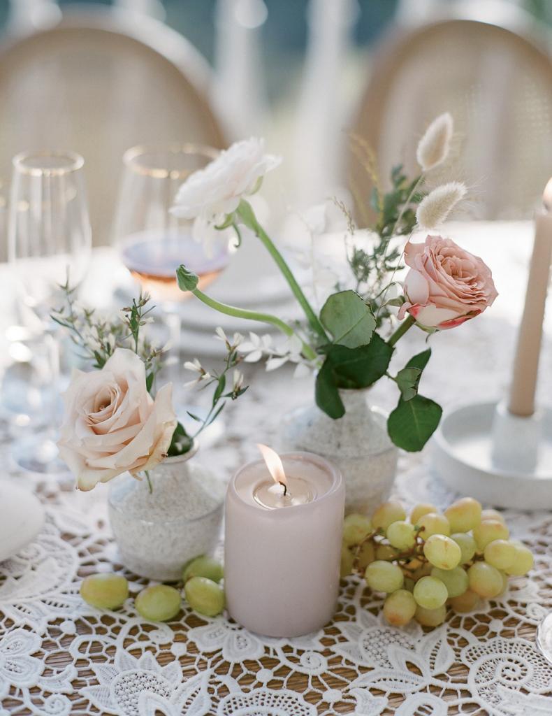 Cluster bud vases filled with select flowers, fresh fruit, and candles for a relaxed tablescape.