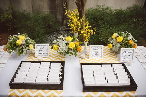 SIT A SPELL: Guests found their seat numbers thanks to a playful escort card design. Jacqueline explains the method behind her display: “Instead of organizing all of the cards on ribbon or in trays, we did both, mixing them with candles and floral arrangements.”