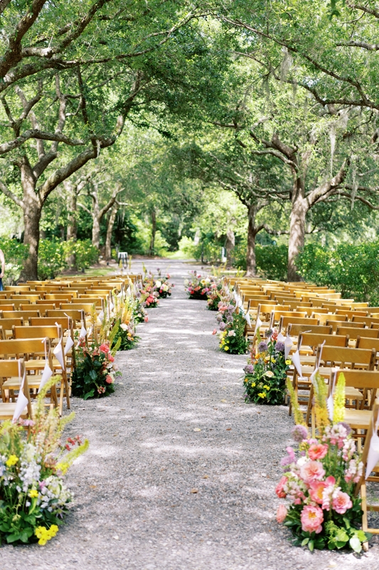 The estate’s tree-lined entrance provided a natural aisle for the nuptials—and the perfect canvas for Festoon Charleston’s eye-catching arrangements.