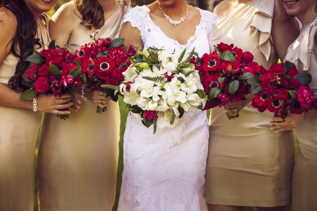 RICH HUES: Tiger Lily crafted the crimson ceremony florals for the bridesmaids, while the bridal bouquet was awash in white.