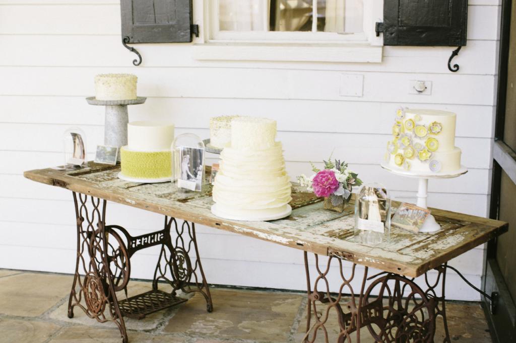 COME ORIGINAL: Forget the folding table—Sarah arranged wedding cakes upon an old farmhouse door supported by twin cast-iron Singer sewing machine bases.