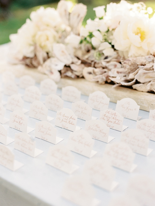 Classic escort cards stood at attention before clusters of shells mixed with fluffy blooms.