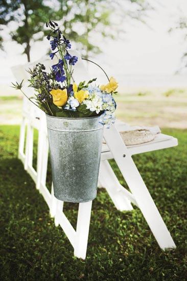 JUST PICKED: In keeping with the wedding’s casual feel, blue thistle, delphinium, freesia, and hydrangea were loosely dropped into metal buckets.