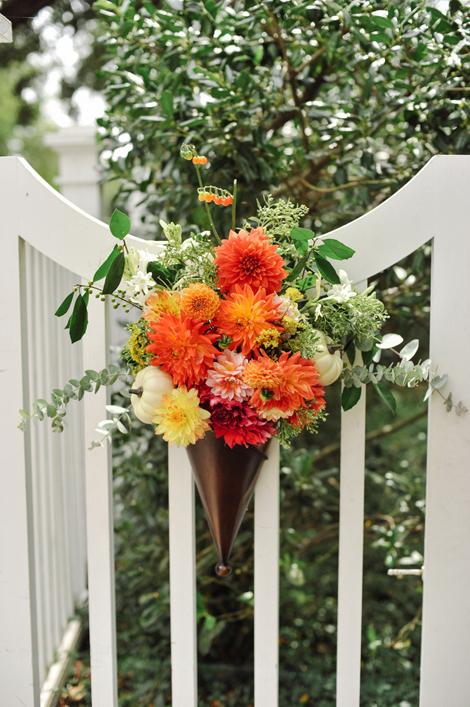 HUNG WITH CARE: Adorning the Governor Thomas Bennett House&#039;s fence were inverted copper cones bursting with orange and yellow dahlias and mums, eucalyptus leaves, and mini pumpkins.